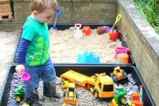 a mini sand box and a mini toy playground with colorful toy cars for a little boy to spend time outdoors