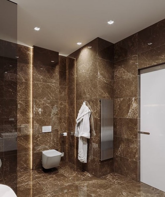 a minimalist brown bathroom clad with brown marble tiles, with white appliances and touches of stainless steel