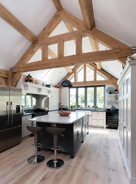 a modern barn kitchen with wooden beams, white cabinets and a black kitchen island plus black appliances looks cool and fresh