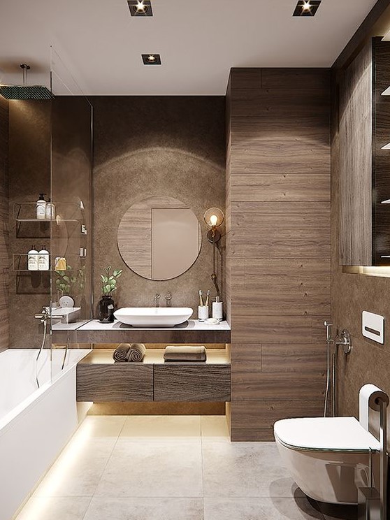 a modern brown bathroom clad with wood like tiles, a floating vanitu and a storage unit, white appliances