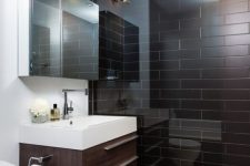 a modern chocolate brown and white bathroom with brown tiles in the shower, a brown vanity and white appliances and walls
