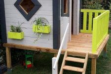 a modern kids’ playhouse in black and white, with neon yellow planters attached to the wal and railing is a stylish idea