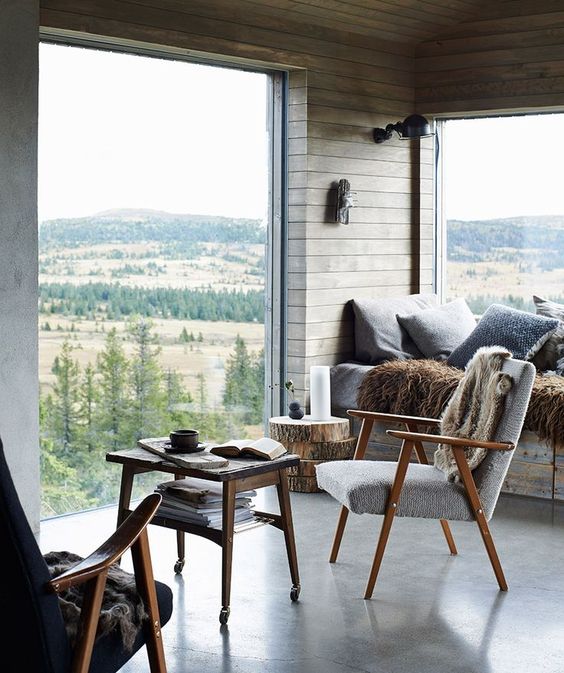 a modern rustic cabin with planked walls, floor to ceiling windows that let the owners enjoy the fab views of the woodlands