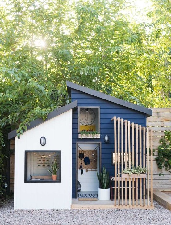 a navy playhouse with a planked porch and a wall mounted seat, potted greenery looks like a real mid century modern house