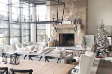 a neutral barn living room with a stone fireplace and wooden beams, creamy seating furniture, and a dining space as an addition