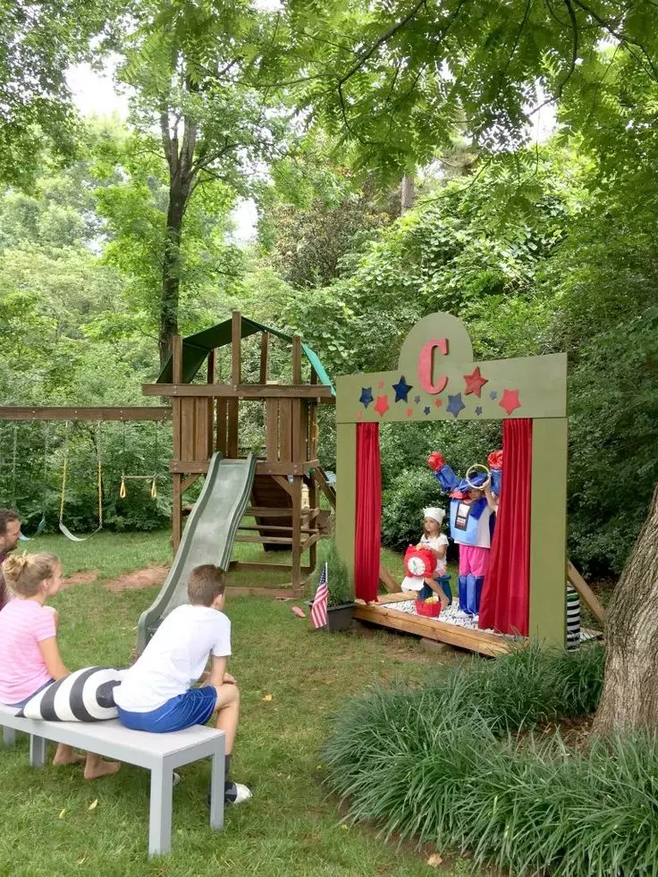 a pretty and fun outdoor backyard kids' theater with a scene, a slide and some benches for watching plays