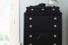 a pretty black vintage dresser with potted greenery on top will add a chic and refined touch to any space
