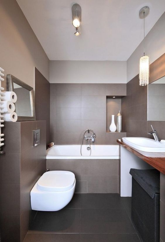 a pretty modern bathroom clad with brown tiles, with a black floor, a simple vanity with a large sink and a tub
