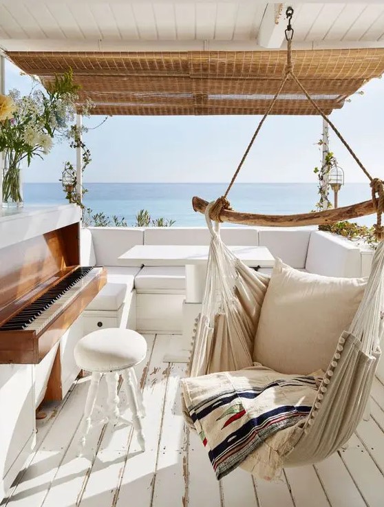 a seaside terrace with a wooden deck, a hanging chair, a sofa, a piano and a cool sea view is amazing