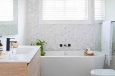 a serene bathroom with marble hex tiles and large scale ones, a wooden vanity and a bathtub plus a shower space