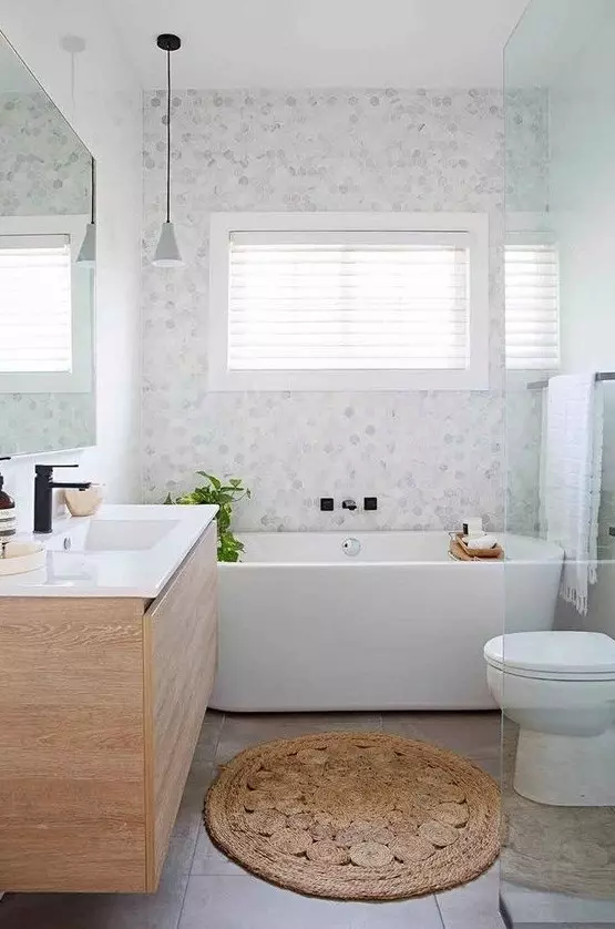 a serene bathroom with marble hex tiles and large scale ones, a wooden vanity and a bathtub plus a shower space