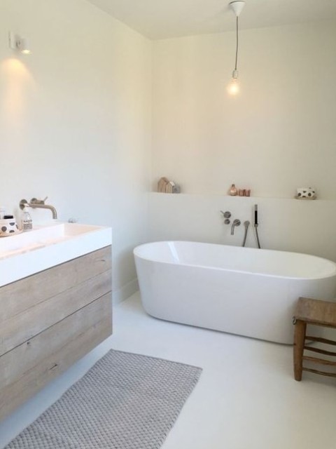 a serene white Nordic bathroom with an oval bathtub, a wooden vanity and a cozy rug is classics of Scandi style