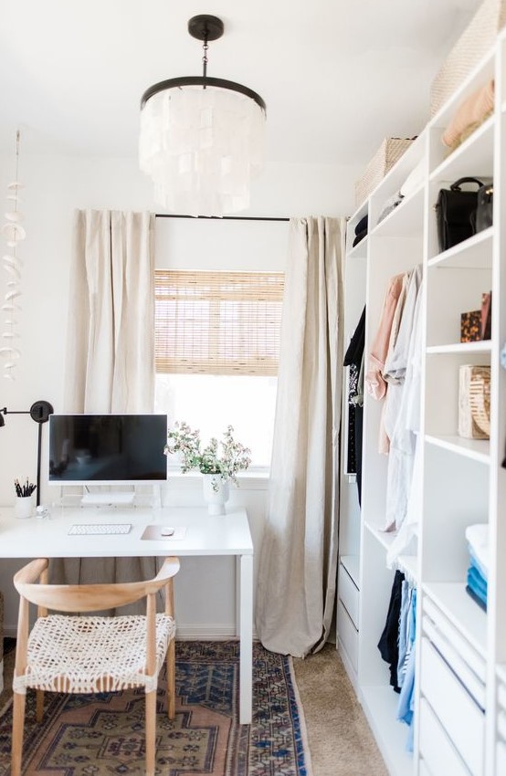 a small and neutral cloffice with a white makeshift closet, a white desk and woven chair, a paper lamp and a printed rug