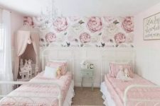 a sophisticated shared girls’ bedroom with white metal beds, pink and white bedding, white paneled walls, a pink canopy over a doll house