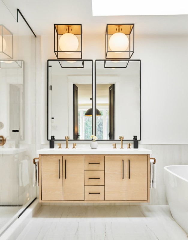a stylish light stained plywood floating vanity with a white stone countertop and black handles looks eye catchy and matches the style of the space