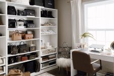 a stylish neutral cloffice with a large white shelving unit, a white desk and a leather chair, a basket fro storage and a white faux fur stool