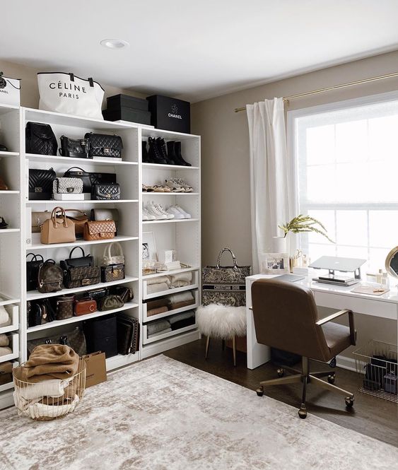 a stylish neutral cloffice with a large white shelving unit, a white desk and a leather chair, a basket fro storage and a white faux fur stool