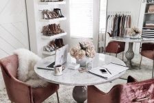 a super glam cloffice with an oversized mirror, a crystal chandelier, dusty pink velvet chairs, a vintage table and open shelves for shoes