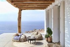 a super relaxed beach terrace with woven beanbag chairs, a rug, a low coffee table and potted plants feels very boho