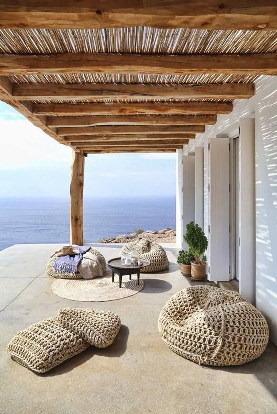 a super relaxed beach terrace with woven beanbag chairs, a rug, a low coffee table and potted plants feels very boho