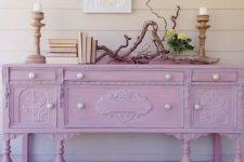 a vintage dresser painted light pink and with pearl knobs, with vitnage books, wooden candleholders and driftwood is adorable for a feminine space