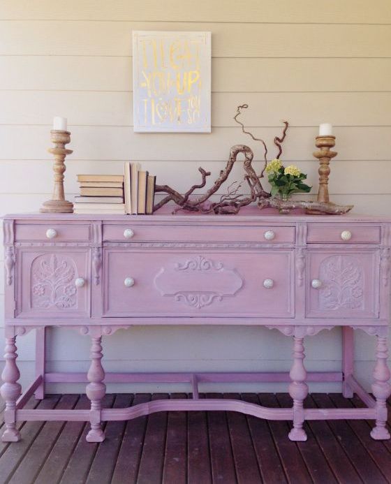 a vintage dresser painted light pink and with pearl knobs, with vitnage books, wooden candleholders and driftwood is adorable for a feminine space