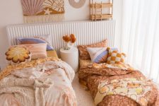 a warm-colored boho shared girls’ bedroom with a rattan bed and a low one with matching bedding, some art and layered rugs