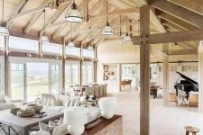 a welcoming barn living room with a stained wooden ceiling and beams and pillars, neutral seating furniture, wooden furniture items and a piano