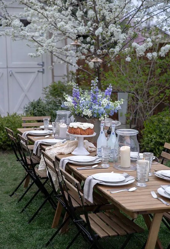 a welcoming dining zone with a wooden table and wooden and metal chairs, neutral linens and blooming trees aroun