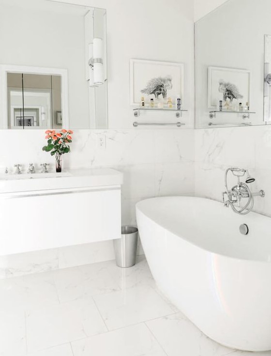 a white bathroom with large scale marble tiles, a tub, a floating vanity and a couple of mirrors