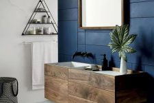 an elegant dark-stained bathroom vanity with drawers looks very eye-catchy on a contrasting navy patterned wall and adds interest to the space