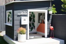 an elegant modern playhouse painted black and white, with a window, some lovely decor inside and potted plants is super cool