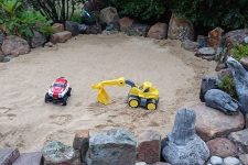 an inspiring outdoor kids’ space for playing, a sand pit with large cars is a cool idea for a rustic outdoor space