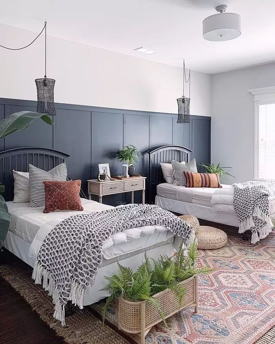 a boho shared guest bedroom with black beds and printed bedding, black woven pendant lamps and greenery