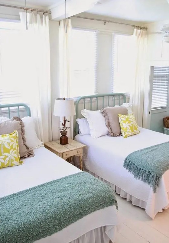 a cozy farmhouse twin guest bedroom with mint-painted beds and large windows