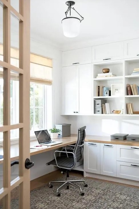 a modern farmhouse home office with white shaker kitchen cabinets, a floating desk and shades plus a printed rug