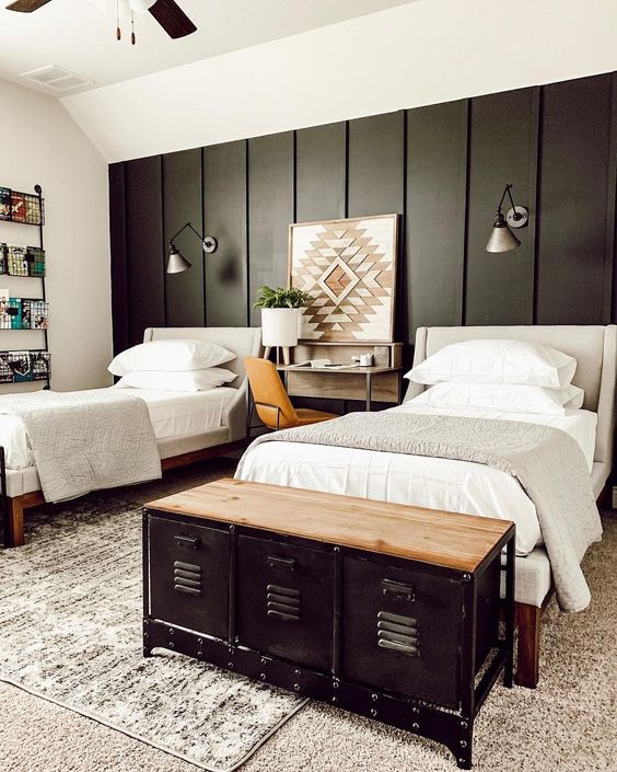 a farmhouse shared guest bedroom with neutral upholstered beds, neutral bedding, a metal chest for storage and metal sconces