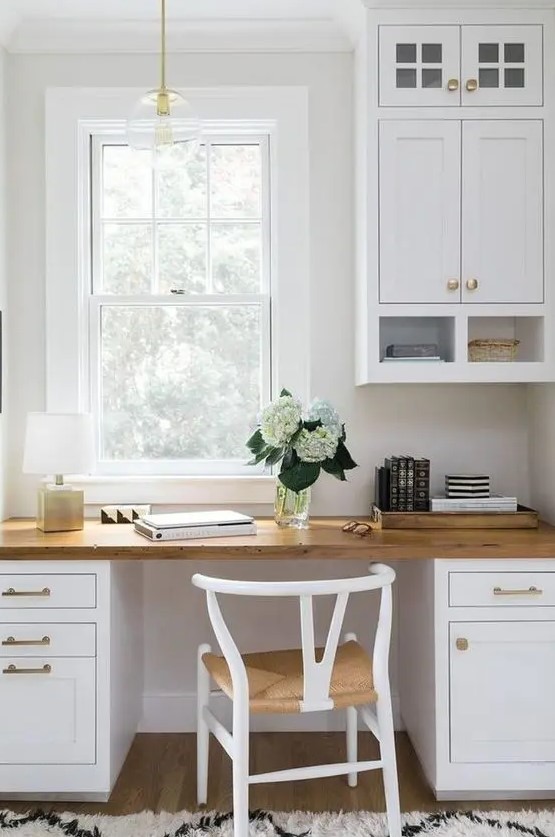 a welcoming white farmhouse home office done with kitchen cabinets and a matching desk, a woven chair and a pendant lamp