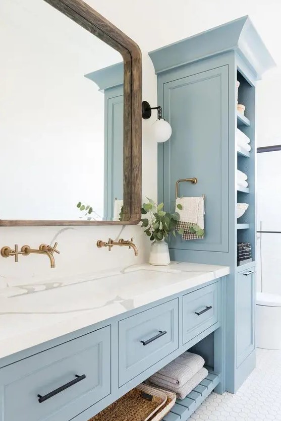 a lovely coastal bathroom done with light blue kitchen cabinets and a vanity that matches, with a white stone countertop
