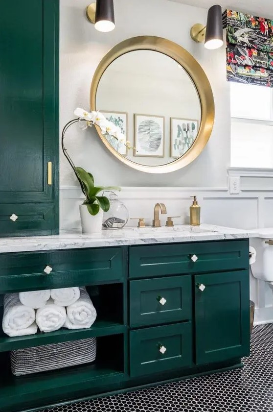 a bright and chic bathroom with dark green kitchen cabinetry, a penny tile floor, some gold touches for more chic