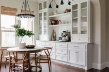 27 a beautiful farmhouse dining space done with white shaker style cabinets, open shelves and black sconces, a round table and wooden chairs