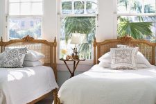 30 a refined vintage shared guest bedroom with wood and cane beds in refined style, neutral bedding and a lovely tropical garden view