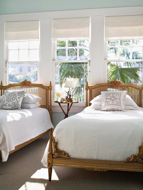 a refined vintage shared guest bedroom with wood and cane beds in refined style, neutral bedding and a lovely tropical garden view