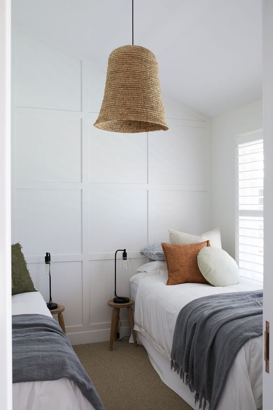a small farmhouse shared guest bedroom with a couple of beds, neutral bedding, wooden nightstands and bulbs, a pendant lamp