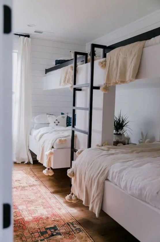 a cozy guest bedroom with two bunk beds and a ladder, with much natural light and pompom blankets