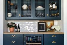 40 an elegant home bar done with navy kitchen cabinets, glass and usual ones, with a wine cooler and a subway tile backsplash plus a butcherblock countertop