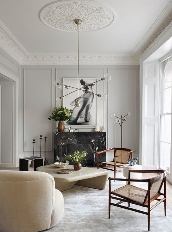 a beautiful and stylish living room that stands out with a large ceiling medalltion, a black marble fireplace, a stone slab table and chic furniture