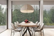 a bold contemporary dining nook with fantastic views of the forest, a living edge table, neutral rounded chairs and a pendant lamp