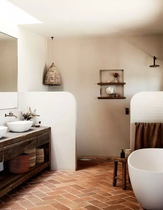a catchy rustic bathroom with half walls that separate the toilet and shower spaces, an oval tub and a reclaimed wooden vanity