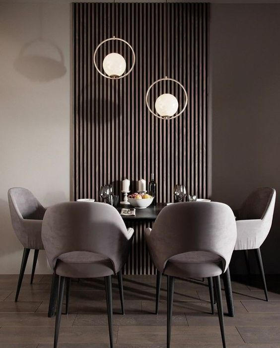 a chic contemporary dining room with a dark wooden slats on the wall, a black table, grey chairs and catchy pendant lamps